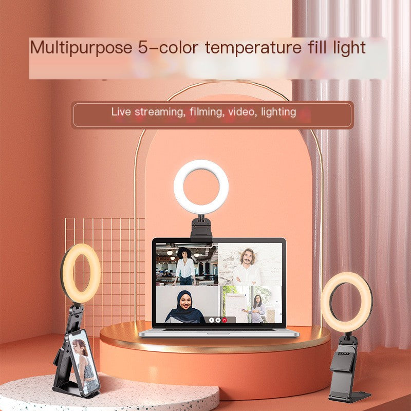 Ring light with stand on a laptop screen displaying a video call, set against an orange wall.