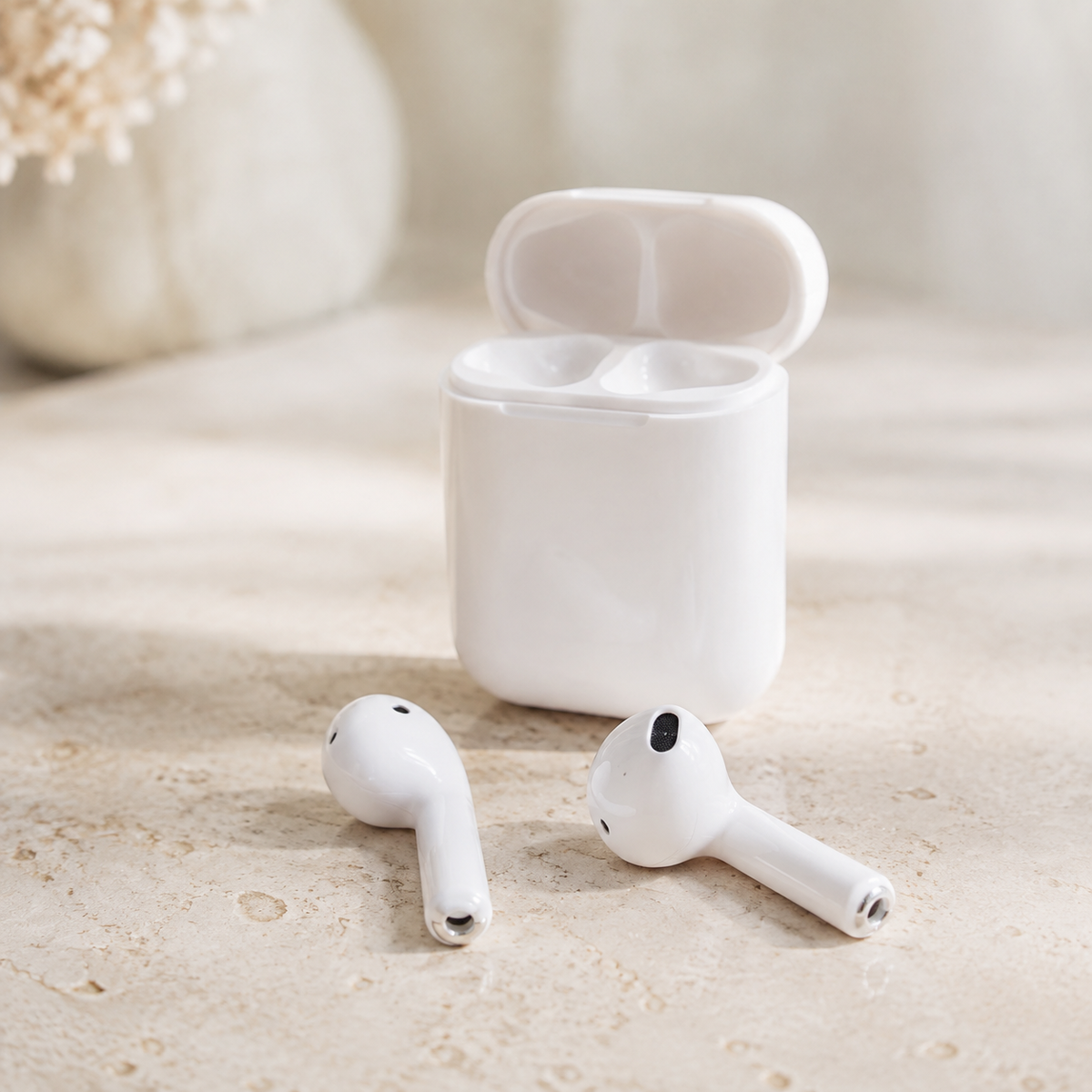 White i7s-style wireless earbuds with charging case on a neutral desk